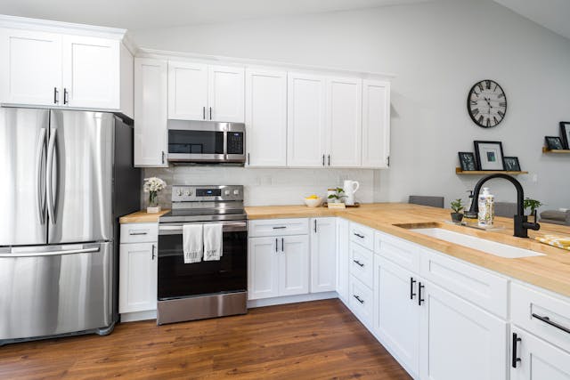 a white kitchen with stainless steel appliances and butcher-block counters